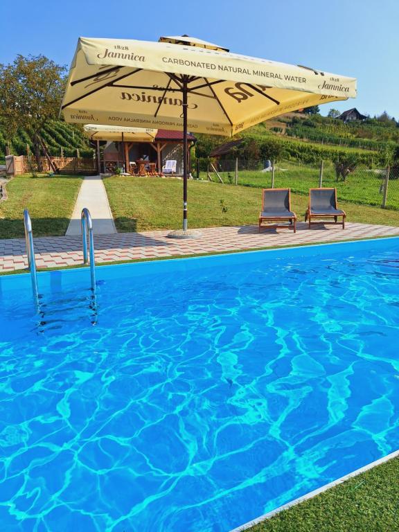 a swimming pool with two chairs and an umbrella at Kuća za odmor Matovilka in Križevci