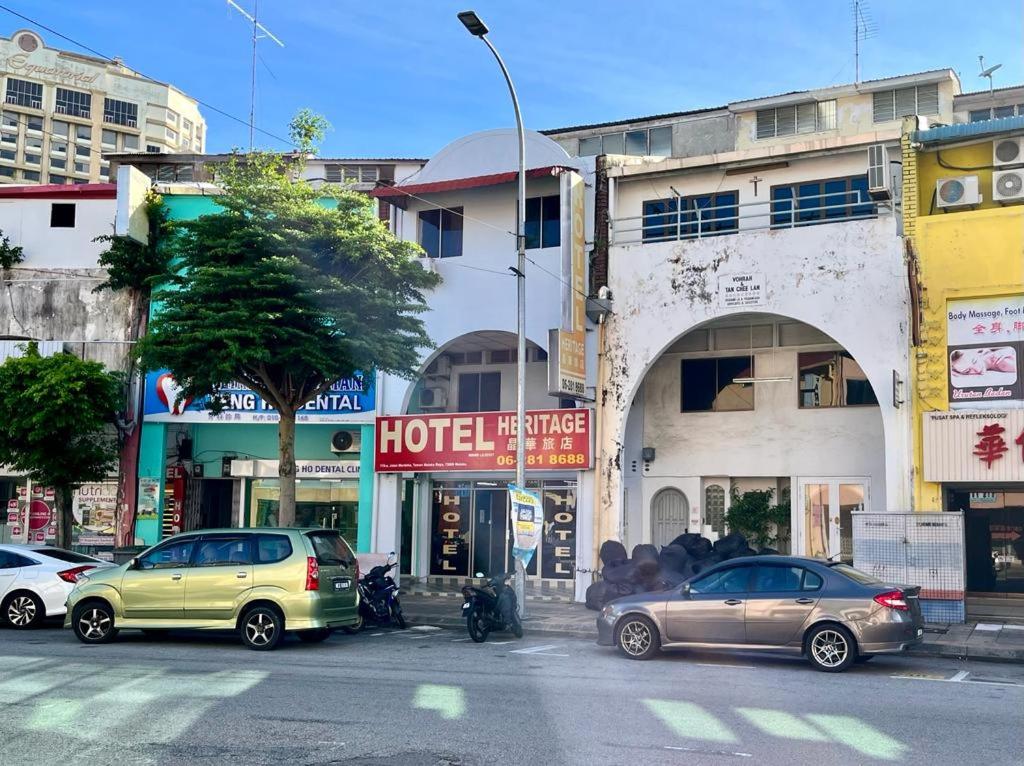 una strada di città con auto parcheggiate di fronte agli edifici di Grand Heritage Hotel a Malacca