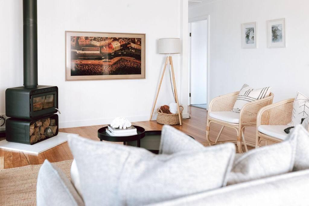 uma sala de estar com um sofá e um fogão a lenha em Omaru Beach House em Scamander