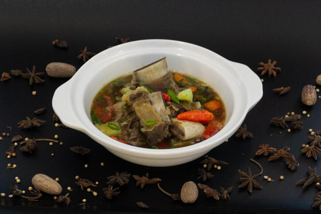a bowl of soup with meat and vegetables and spices at Anara Airport Hotel in Tangerang