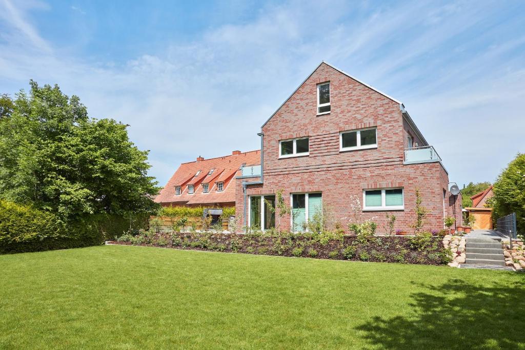 a large brick house with a grass yard at Apartmenthaus Emily by POLY Hohwacht in Hohwacht