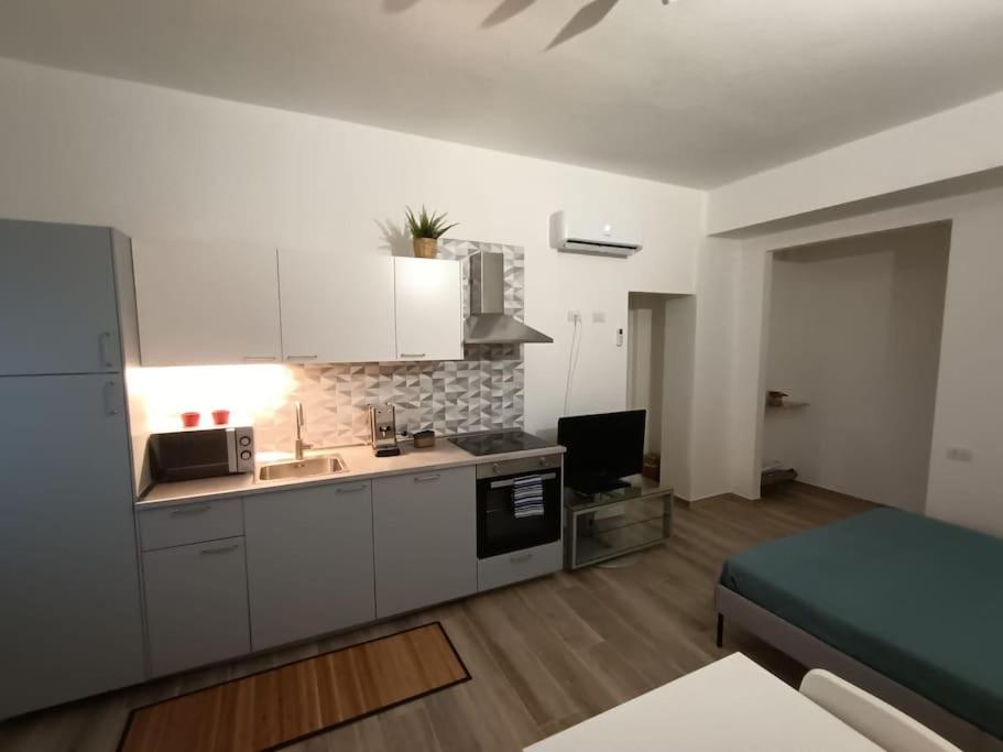 cocina con armarios blancos y lavabo en una habitación en Appartamento Daisy - Parma, en Parma
