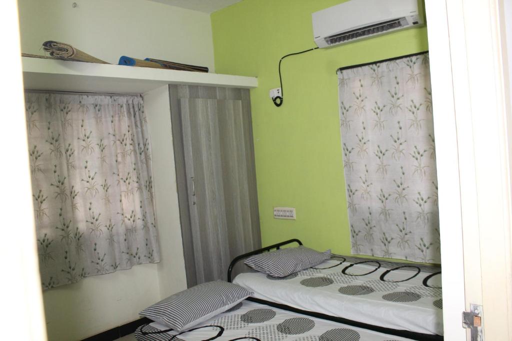 two beds in a room with green walls and windows at Centaurus Homestay near Trichy Airport in Tiruchchirāppalli