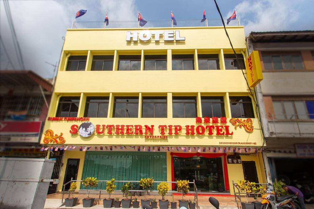 a yellow hotel with a sign on top of it at Southern Tip Hotel in Pontian Kecil