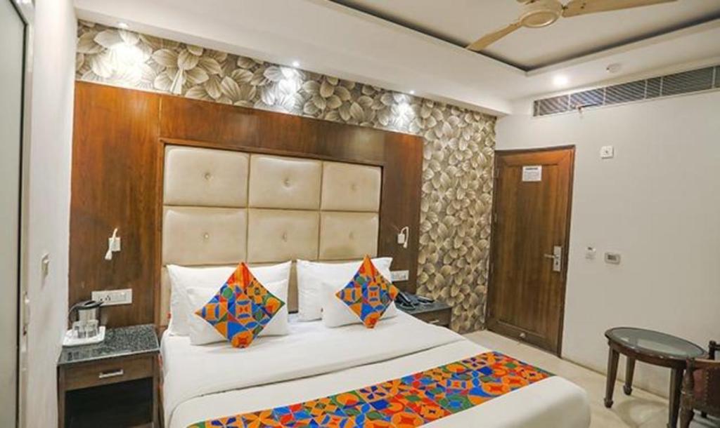 a bedroom with a large bed with a wooden headboard at FabHotel Station I in New Delhi