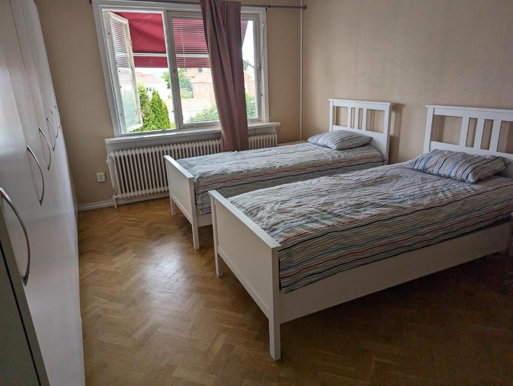 two beds in a room with two windows at Nära till allt in Jönköping