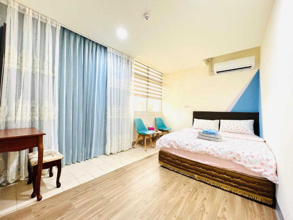 1 dormitorio con cama, escritorio y cortinas en Xingang Ping An B&B en Xingang