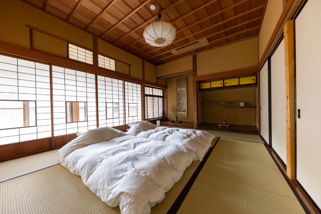 1 cama blanca grande en una habitación con ventanas en ‐izen 高田‐ 楽酔亭, en Joetsu