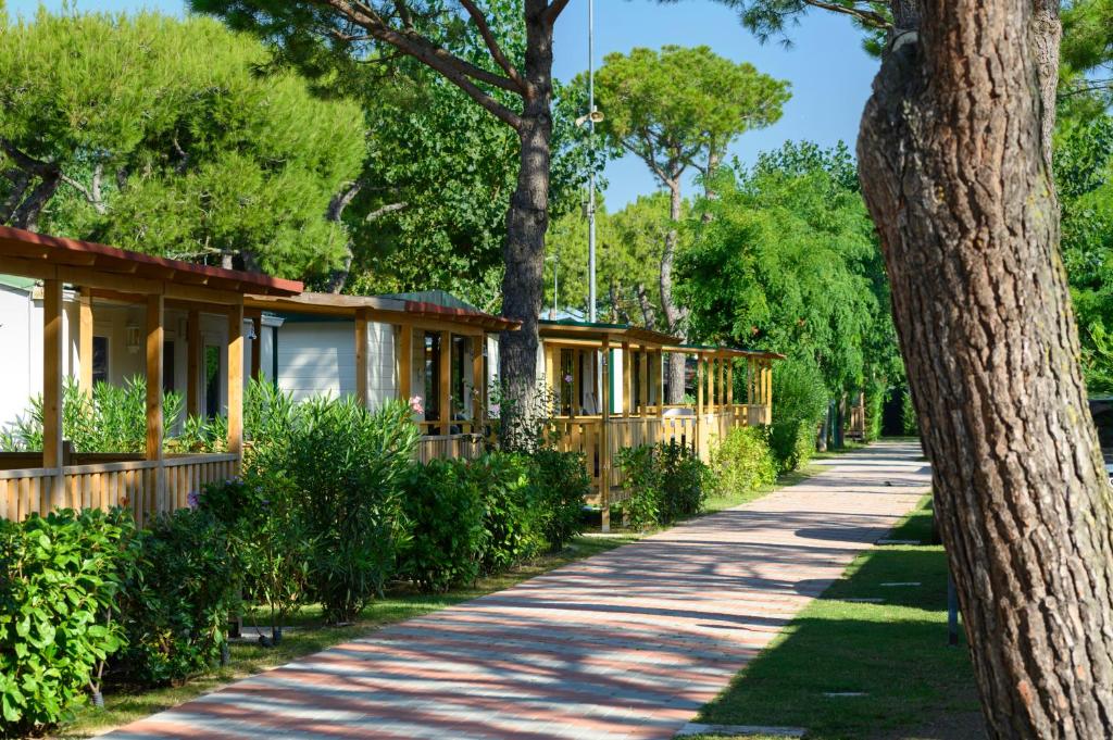 eine Reihe von Cottages auf einem von Bäumen gesäumten Weg in der Unterkunft Ca' Berton Village in Cavallino-Treporti