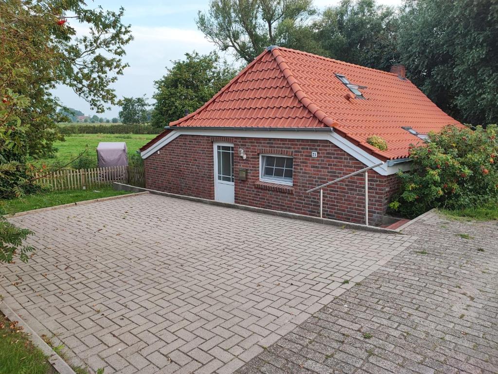 a brick house with a red roof and a brick driveway at Fischerhaus am Deich 45233 in Jemgum