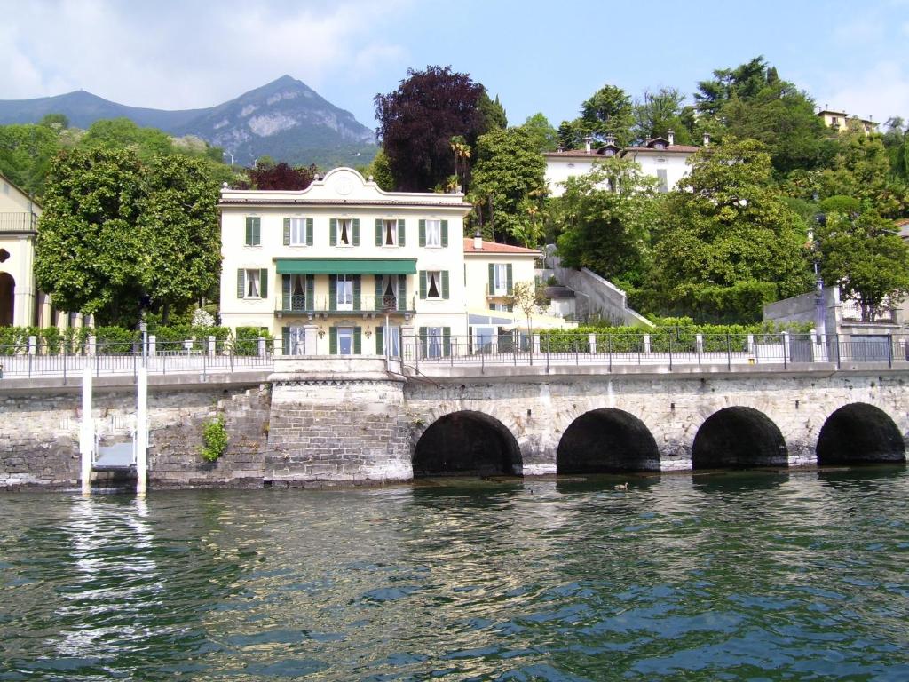 un puente sobre un cuerpo de agua con un edificio en Villa La Mirabella, en Cadenabbia