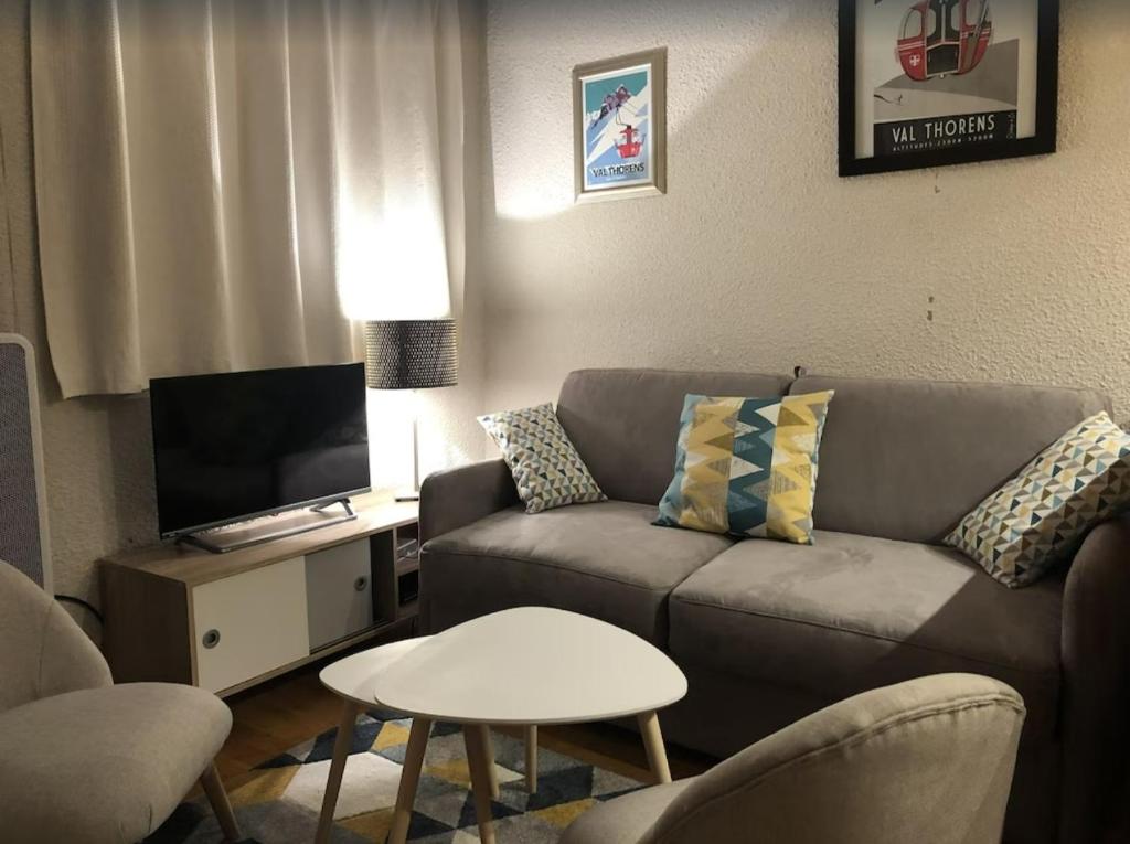 un salon avec un canapé et une télévision dans l'établissement Le Joker Vue Cime Caron Calm & Cosy, à Val Thorens