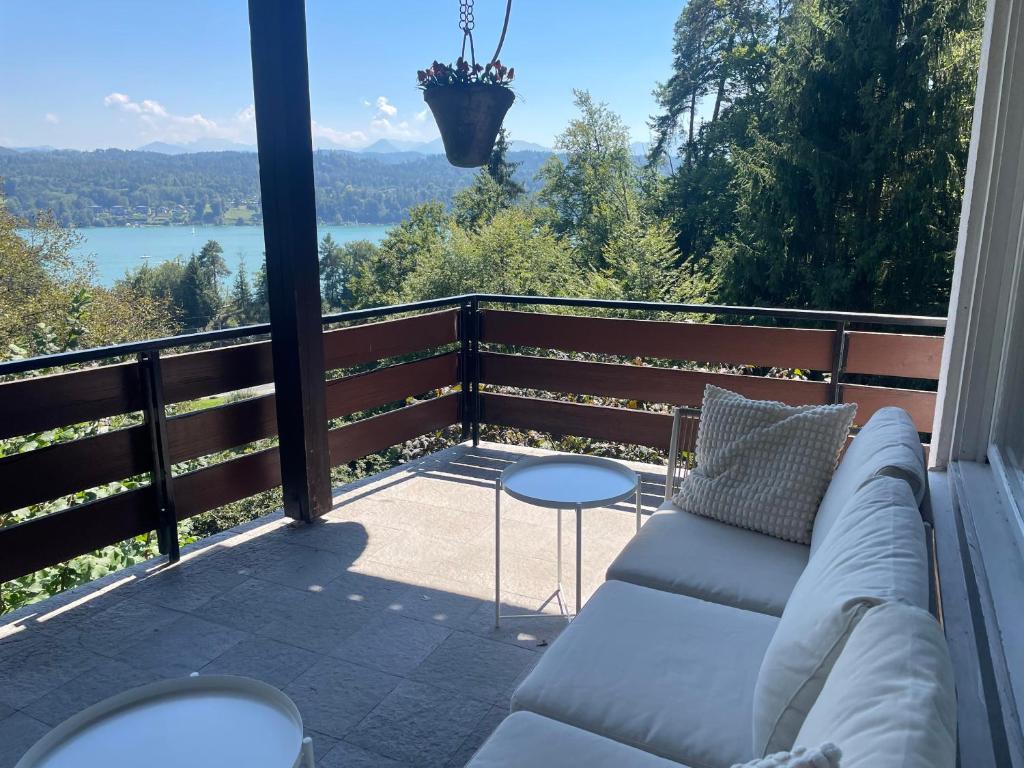 a couch on a balcony with a view of a lake at Haus Magnolia in Techelsberg am Worthersee