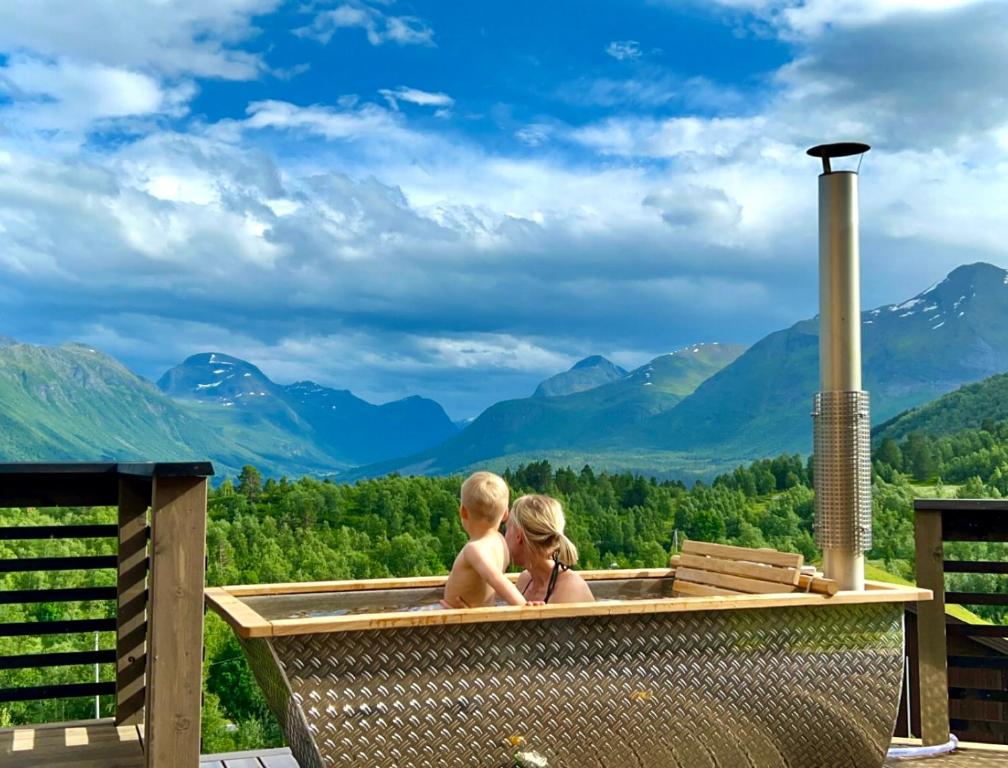 un niño y una niña en un jacuzzi con montañas en el fondo en Unique Romantic Cabin with Mountain View at Strandafjellet, Mivo X en Stranda
