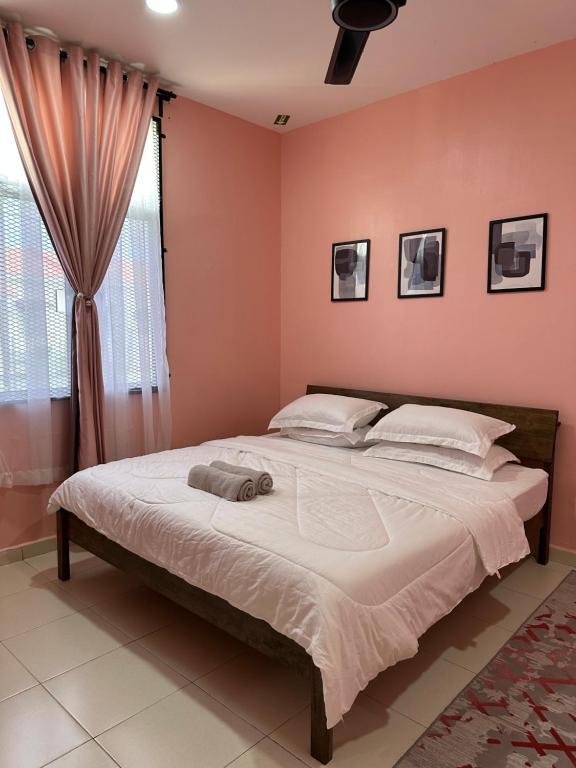 um quarto com uma cama grande e paredes cor-de-rosa em CassaNeyna Homestay Kuantan em Kuantan