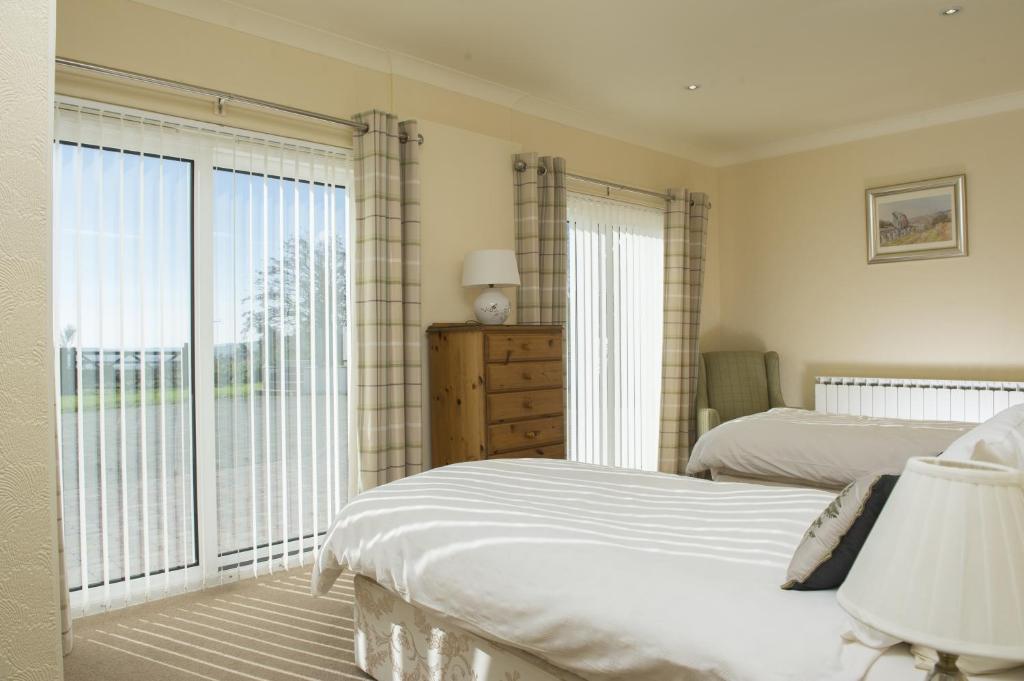 a bedroom with two beds and a large window at Ballachrink Farm Cottages in Laxey