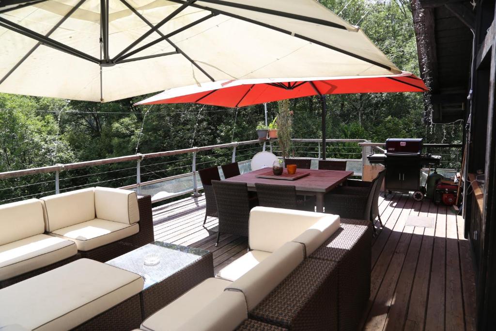 a deck with couches and a table and umbrella at CHALET ELISTHUR in Saint-Jean-d'Aulps