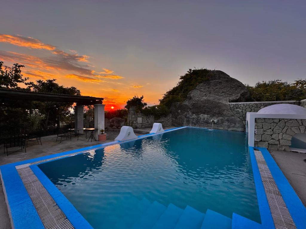 a large swimming pool with a sunset in the background at Il Vitigno di Dioniso in Ischia