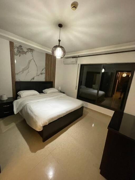 Un dormitorio con una gran cama blanca y una lámpara de araña. en apartment 60m 1bedroom for rent3 en Umm Uthainah