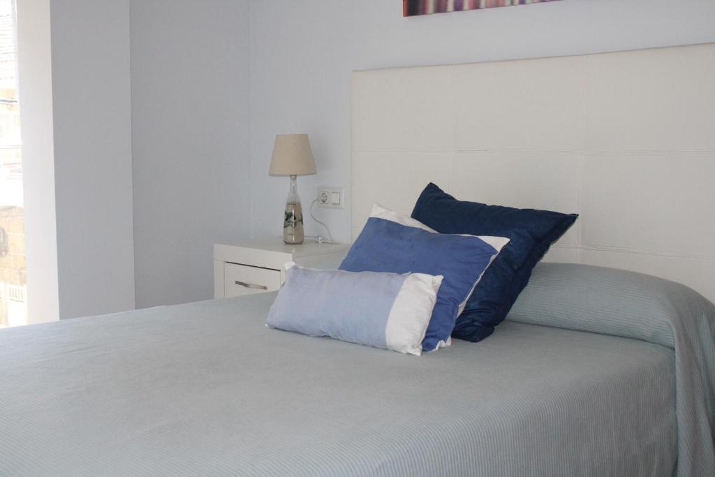 a bed with two blue and white pillows on it at Las Rosas in Vigo