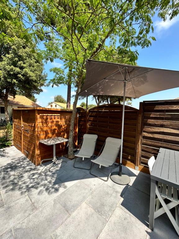 a patio with two chairs and an umbrella at L'évasion des pins - Au coeur de la Nature in Saint-Jean-de-Monts