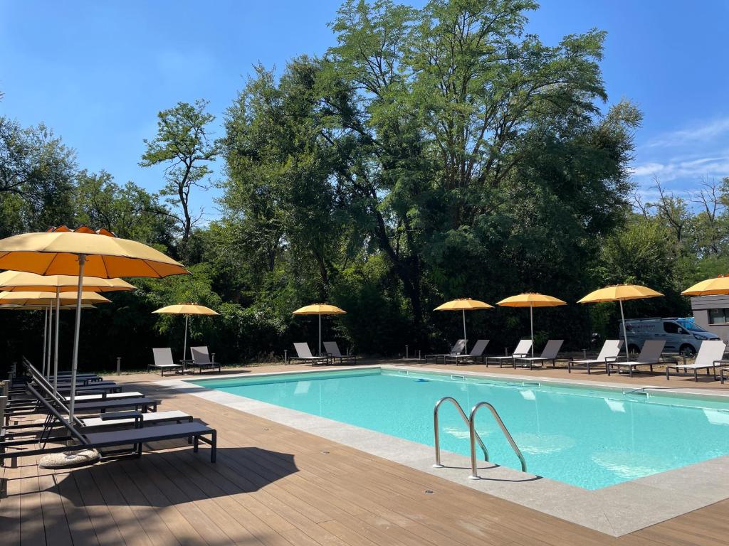 a swimming pool with umbrellas and lounge chairs at Belstay Milano Linate in Peschiera Borromeo