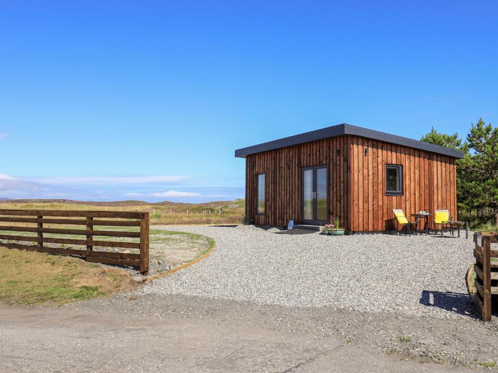 a small wooden cabin with a fence next to it at The Wheelhouse in Carinish