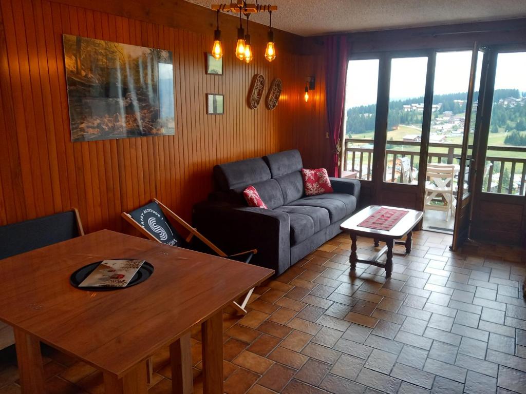 ein Wohnzimmer mit einem Sofa und einem Tisch in der Unterkunft Appartement chalet en plein centre des Saisies in Hauteluce