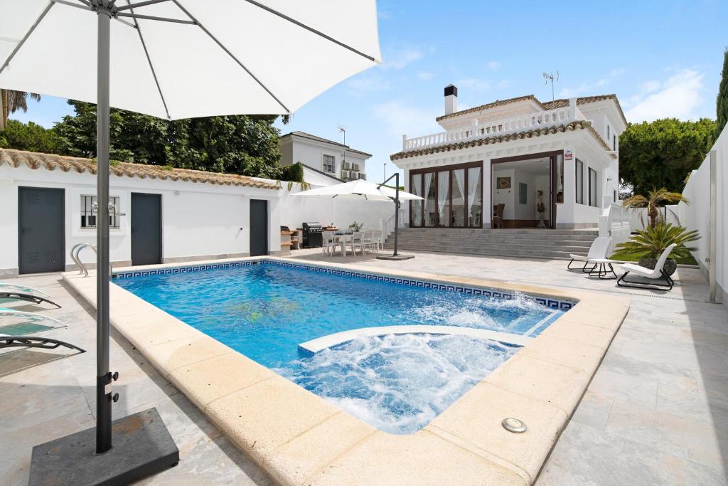 a swimming pool in front of a house with an umbrella at Casa Anna in Novo Sancti Petri