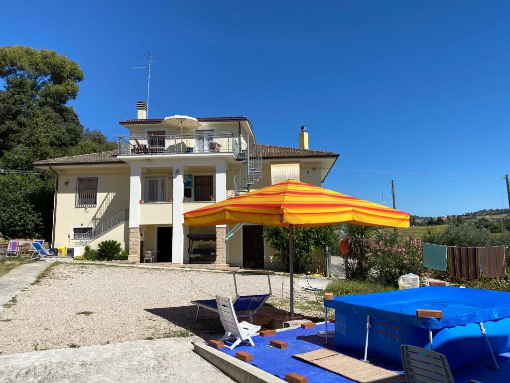 dom z parasolem, stołem i krzesłami w obiekcie Casa vacanze Podere Bellavista w mieście Monteprandone