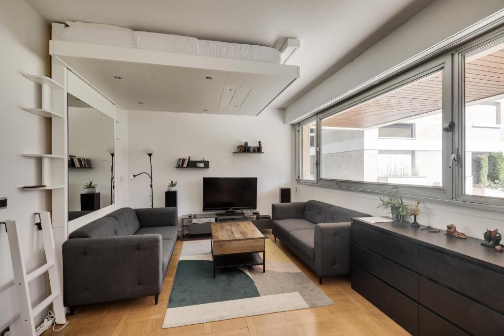 uma sala de estar com dois sofás e uma televisão em Le Nid- Garches em Garches