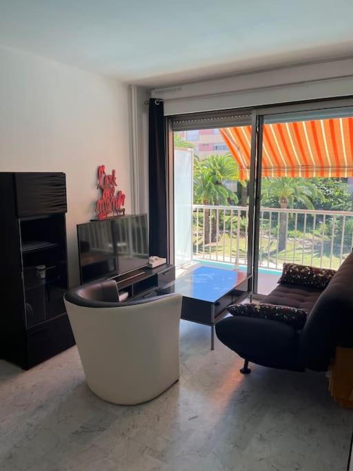 a living room with a couch and a chair and a table at Petit deux pièces avec piscine in Vallauris