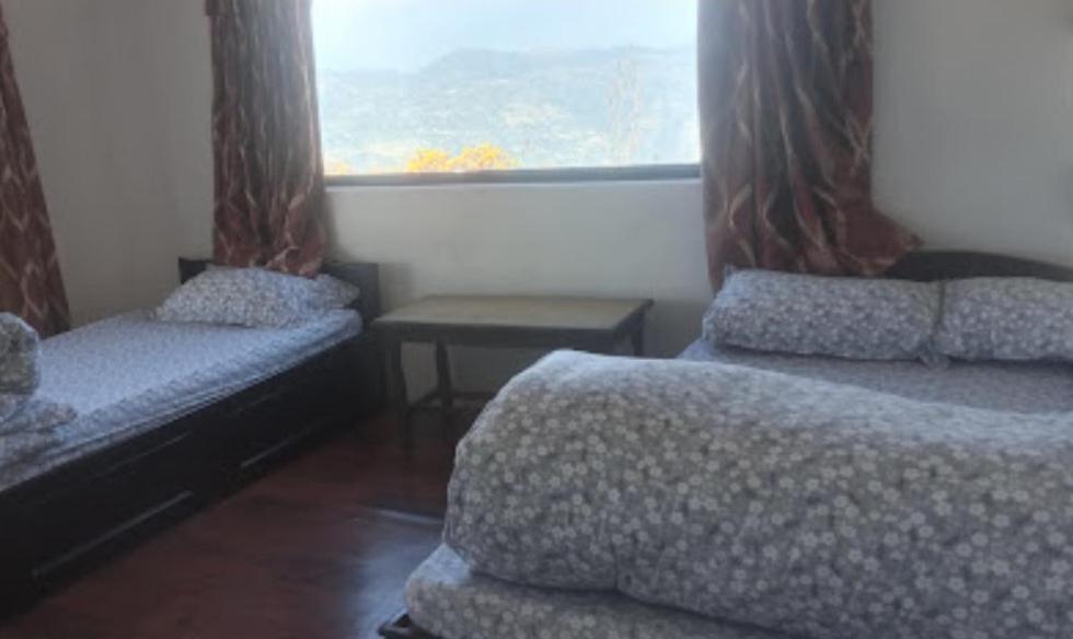 a bedroom with two beds and a window at Juma Danda Lodge in Pokhara