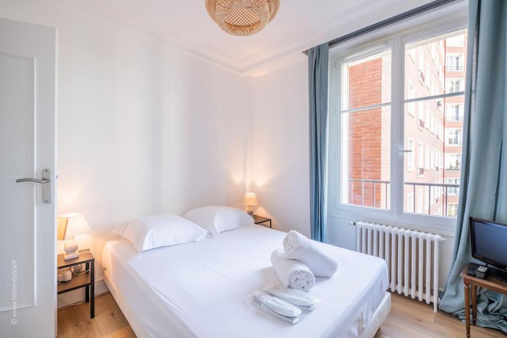 un lit blanc dans une chambre avec une fenêtre dans l'établissement Denfert Rochereau - Wonderful apartment near the Parc des Princes, à Boulogne-Billancourt