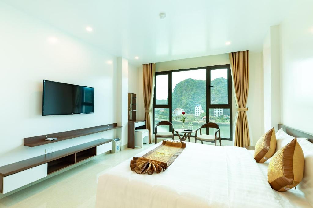 a bedroom with a large white bed with a flat screen tv at Tung Quang Hotel in Cat Ba