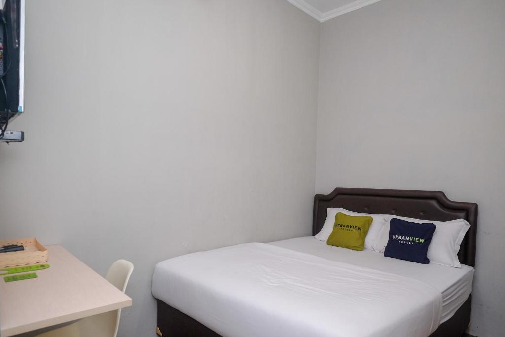 1 dormitorio con 1 cama con 2 almohadas en Urbanview Stay at H jakal by RedDoorz, en Yogyakarta