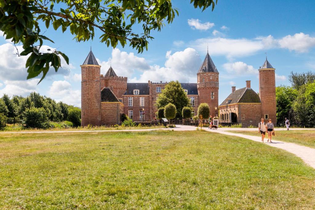 a castle with two people walking in front of it at Stayokay Hostel Domburg - Fully renovated March 2023 in Oostkapelle