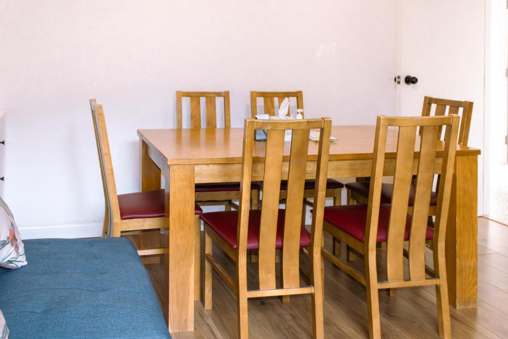 mesa de comedor con 4 sillas y mesa de madera en Nice 4 Bedroom Apartment near City Centre 2-min Walk to Metro !! Business & Family Friendly!!, en Londres