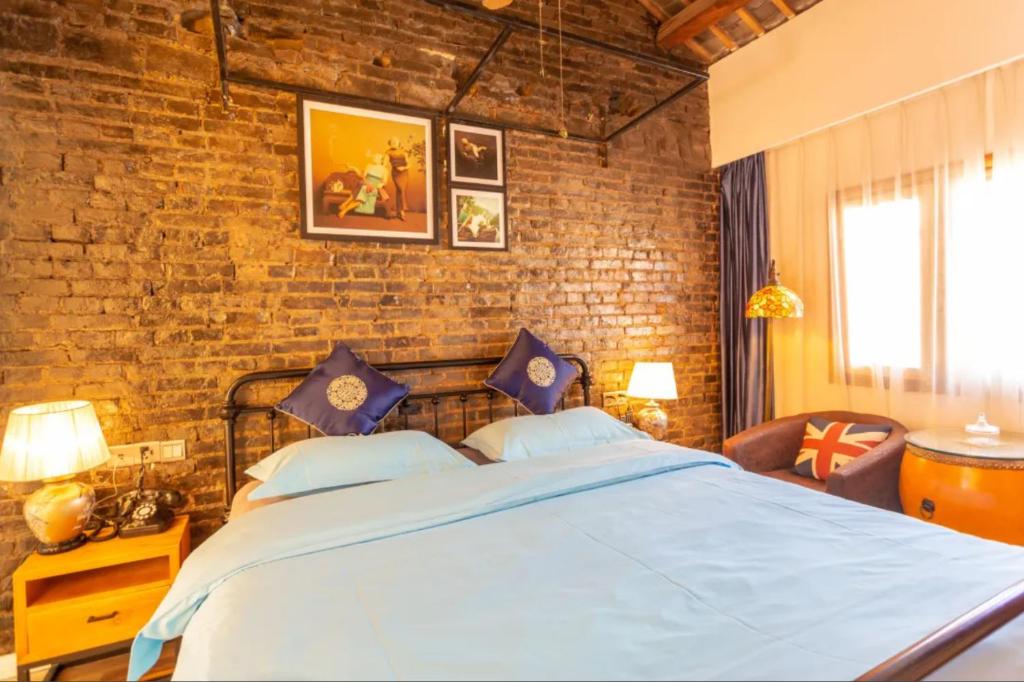 a bedroom with a large bed and a brick wall at Gongxili - Chujian Hotel in Kunming