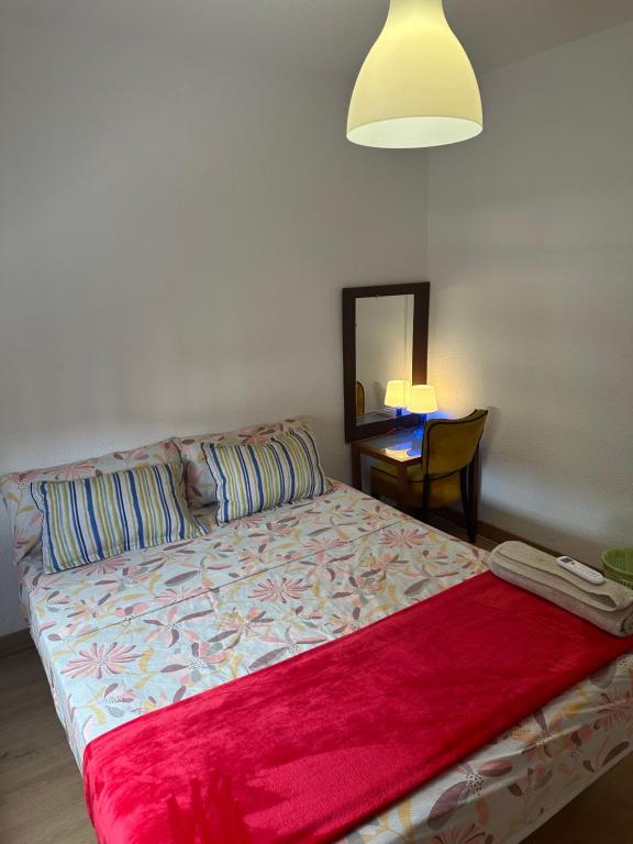 um quarto com uma cama e uma mesa com um candeeiro em El Gengo Hostel em Madri