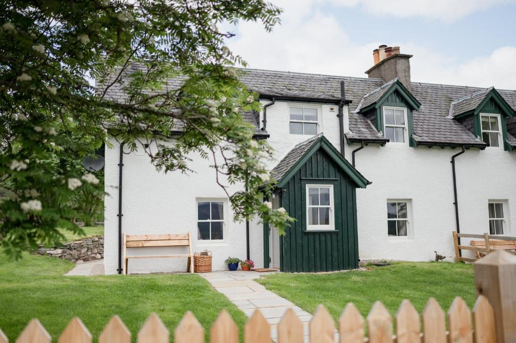 una casa bianca con il tetto verde di Gleann Cottage - Seasgair Lodges a Kincraig