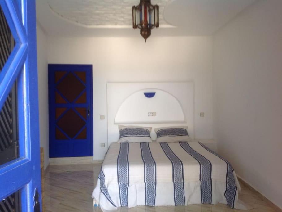 um quarto com uma cama e uma porta azul em belle maison vue sur mer em Oualidia