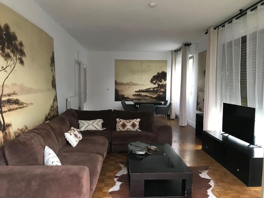 a living room with a brown couch and a piano at résidence Garches -St Cloud in Rueil-Malmaison