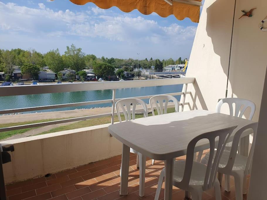 une table et des chaises sur un balcon avec vue sur l'eau dans l'établissement Studio cabine La Lagune Côté Espiguette, au Grau-du-Roi