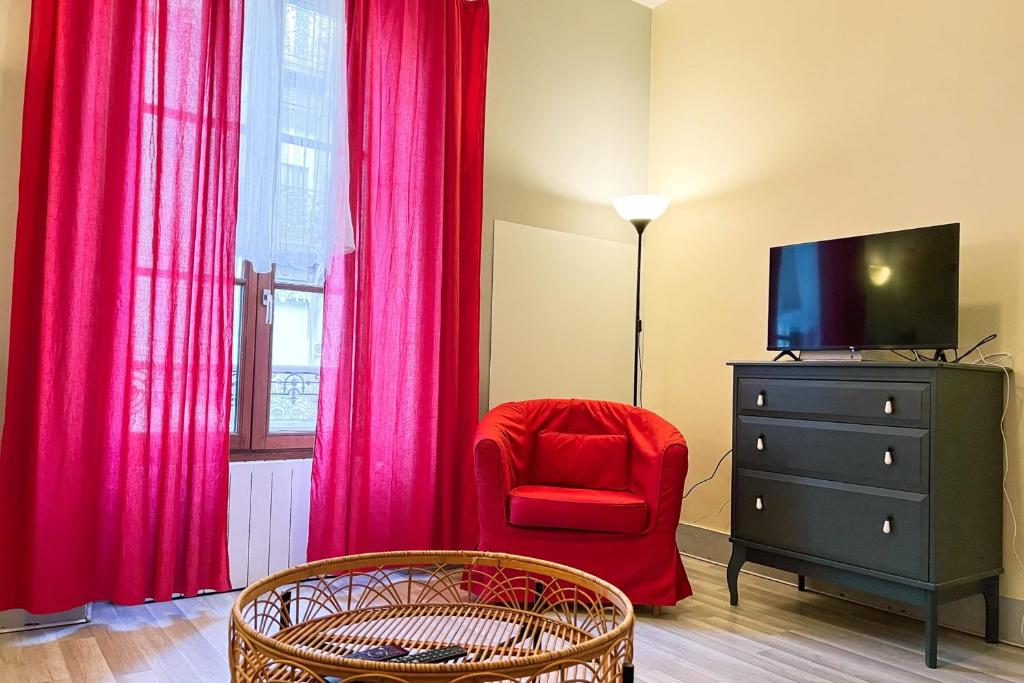 a living room with a red chair and a television at Marx Residence T2 4 personnes - Wifi #EA in Grenoble