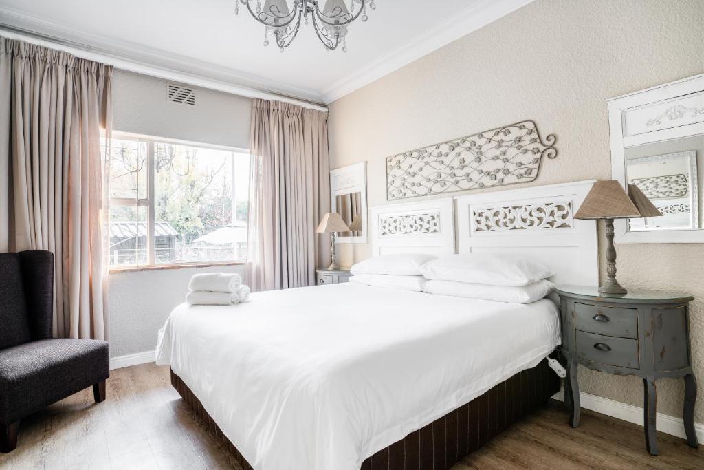 1 dormitorio blanco con 1 cama grande y 1 silla en Avemore Vredehof No 2 - with Backup Power en Stellenbosch