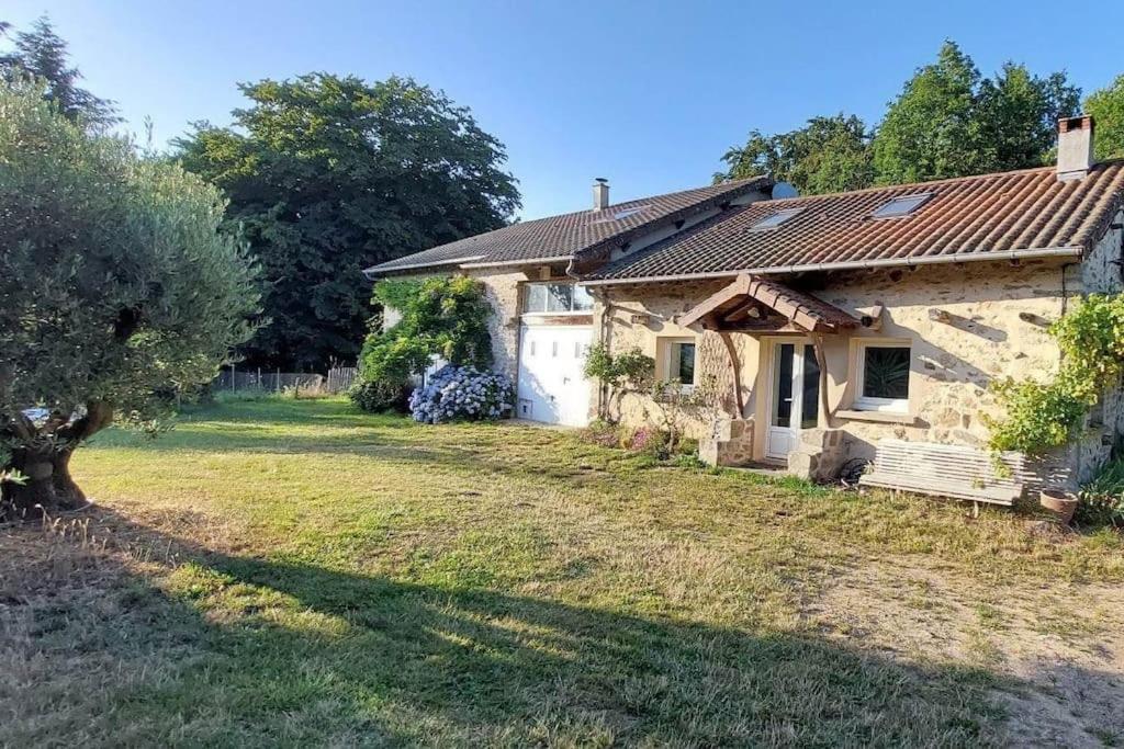 a stone house with a yard in front of it at Maison de la nature in Bussière-Galant