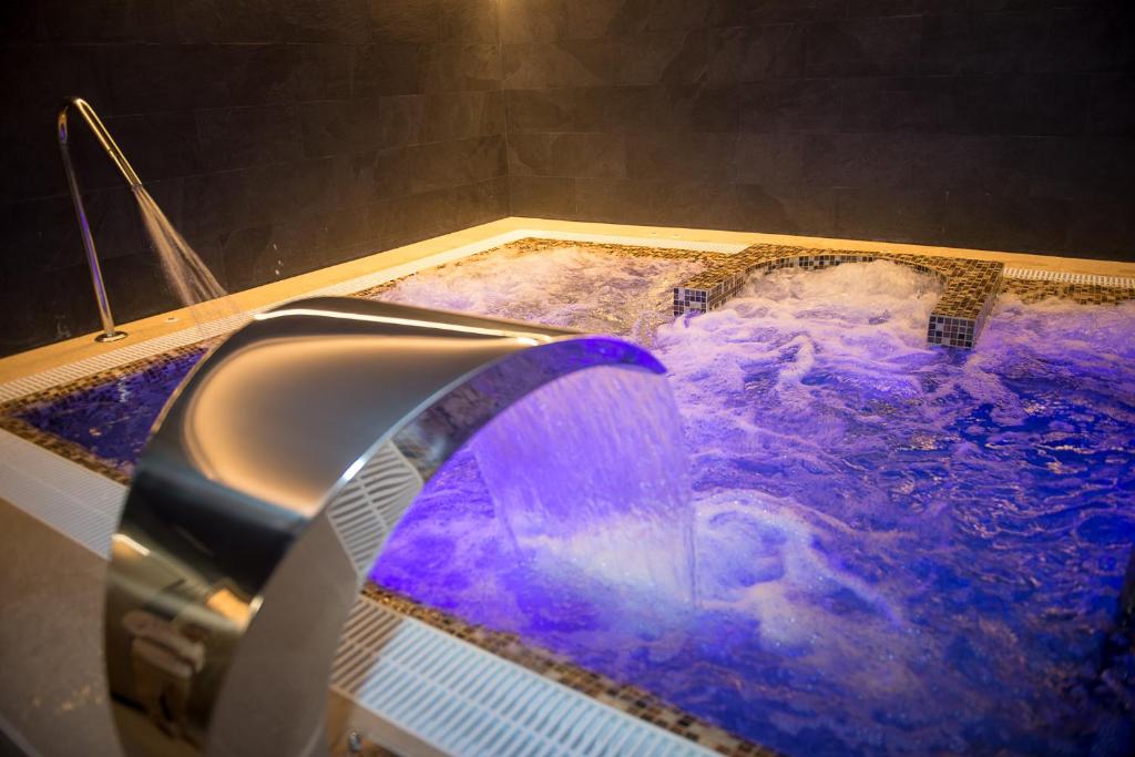 哈卡的住宿－Oroel Hotel & SPA，浴缸、紫色淋浴