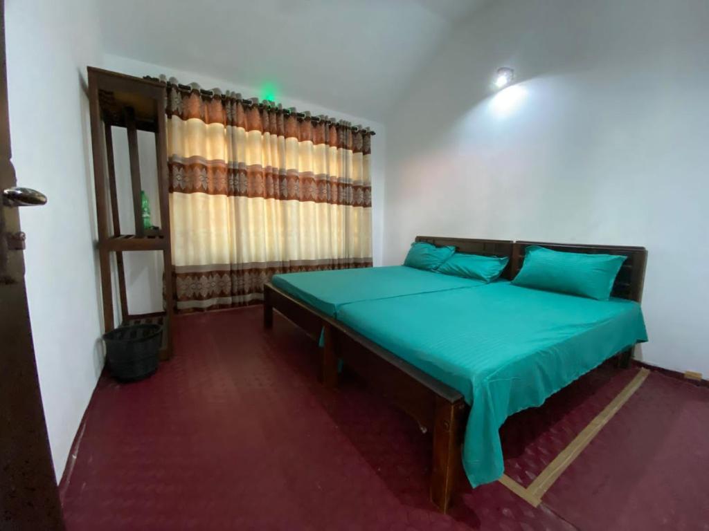 Schlafzimmer mit einem Bett mit grüner Bettwäsche und einem Fenster in der Unterkunft Beach Guest House Addalaichenai in Addalachenai