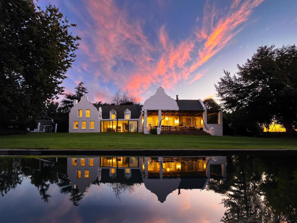 a house with a reflection in the water at dusk at Mount Vernon Manor in Klapmuts
